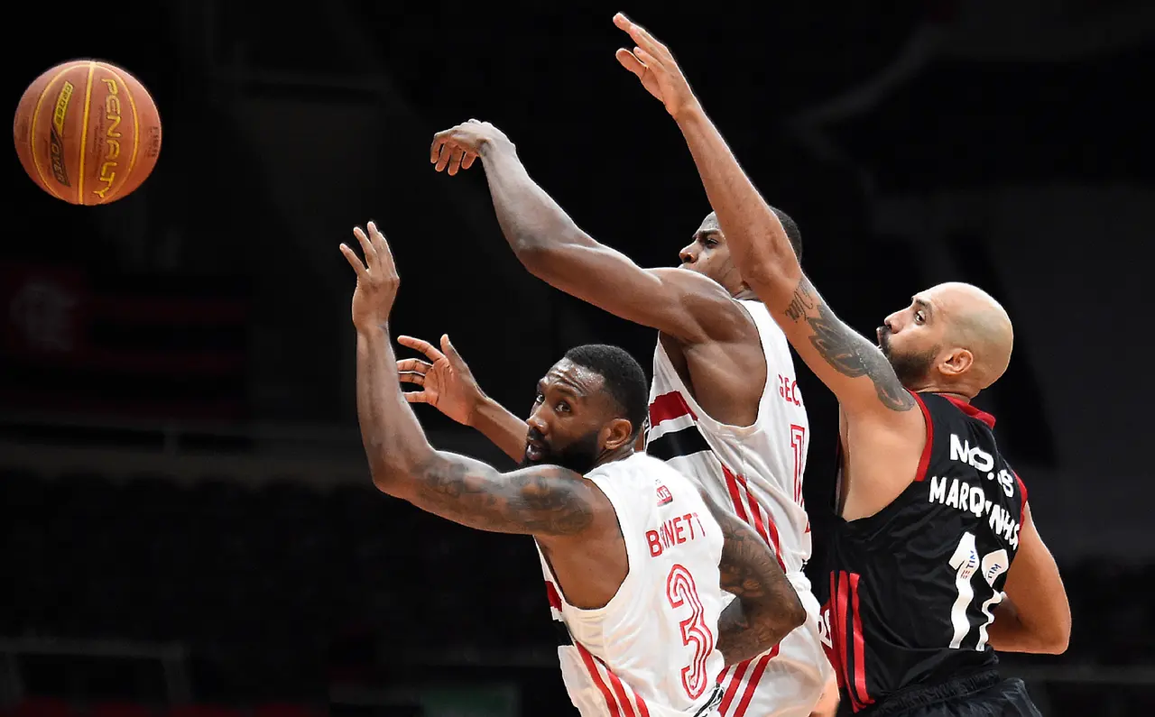 Tre basketballspillere der kæmper om bolden
